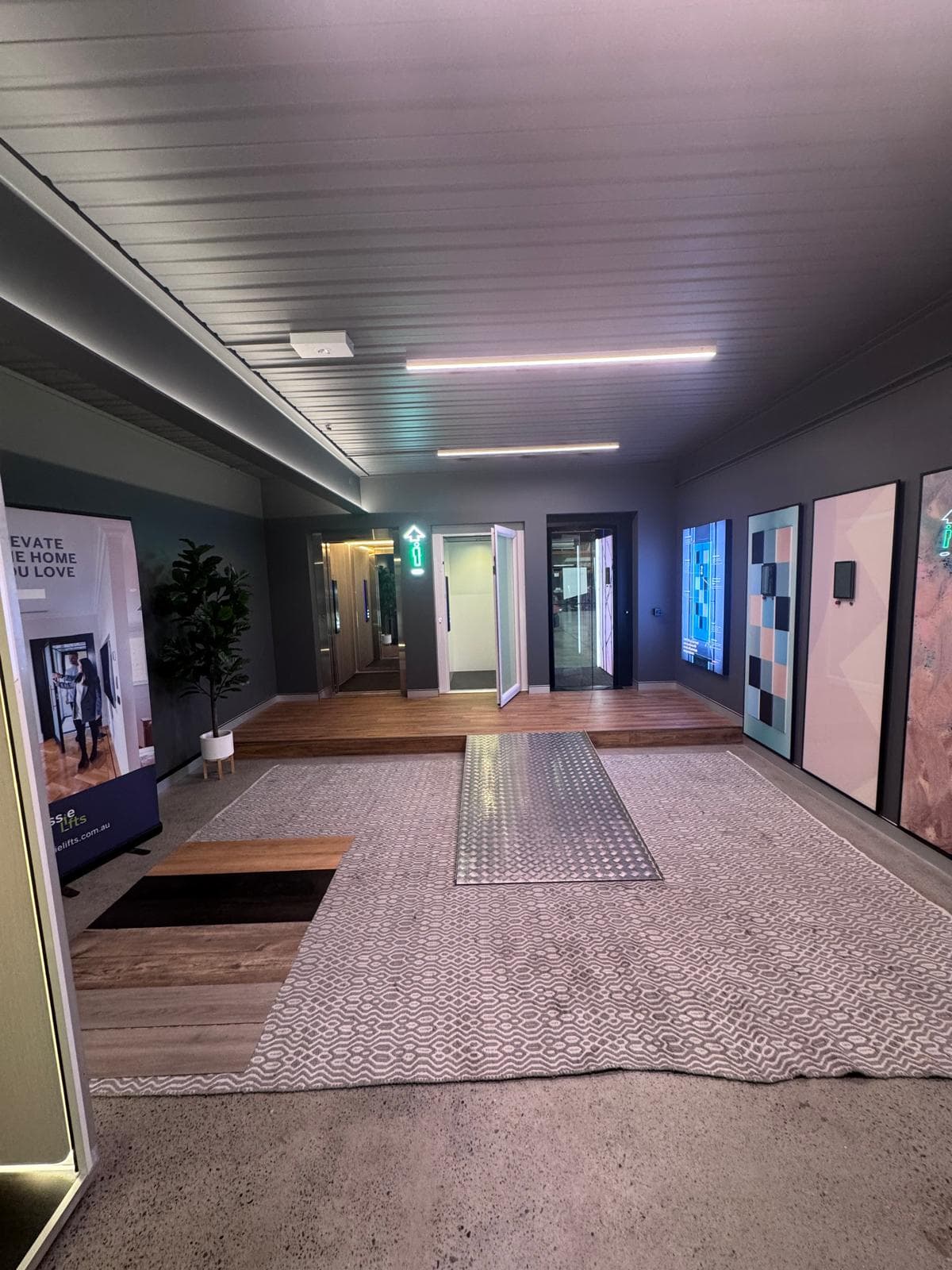 Showroom with lift doors along the back wall, finish panels on the side wall and a raised timber platform