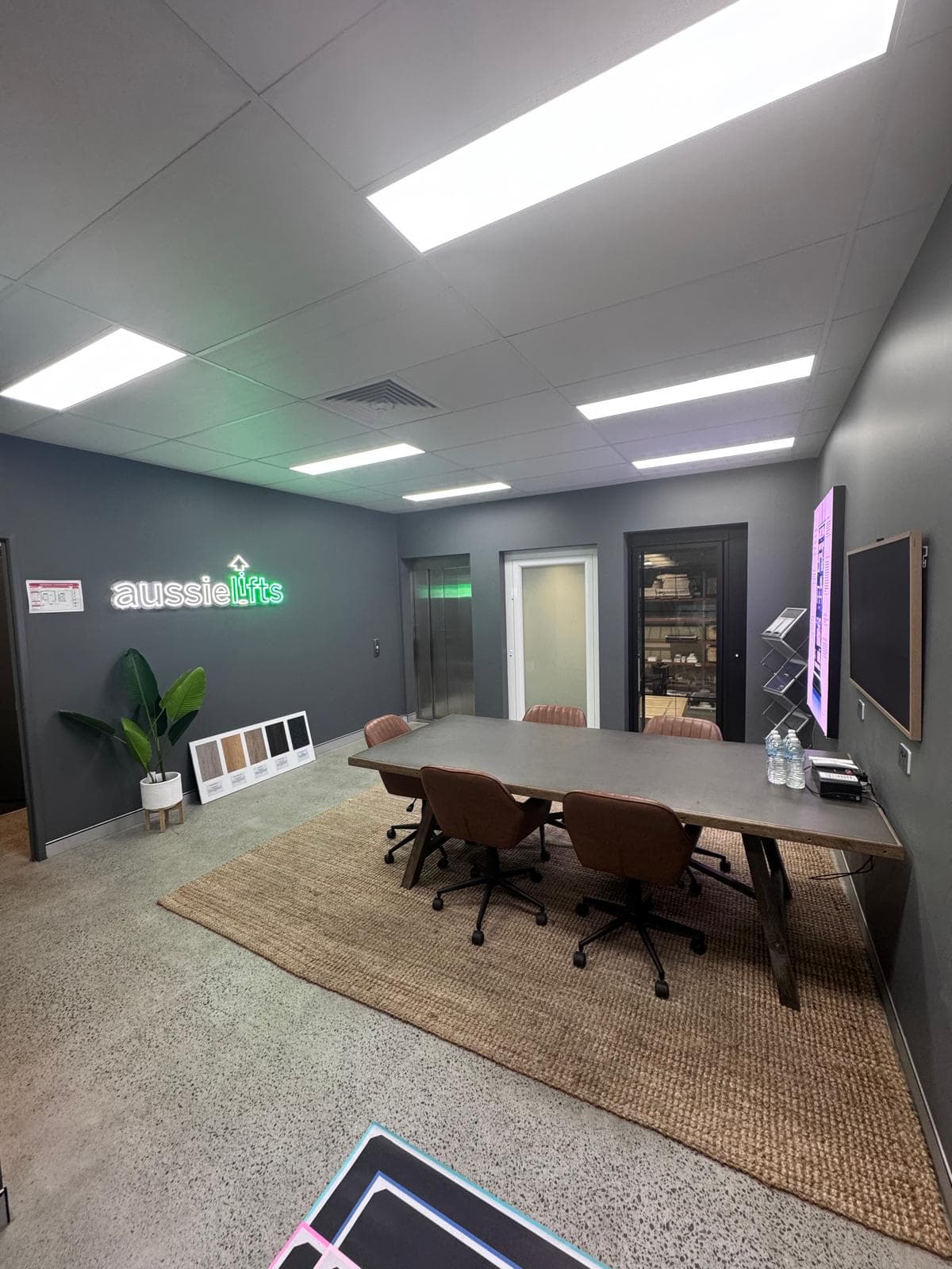 Aussie Lifts Brisbane showroom at Acacia Ridge, a meeting table and finish samples under the illuminated Aussie Lifts sign