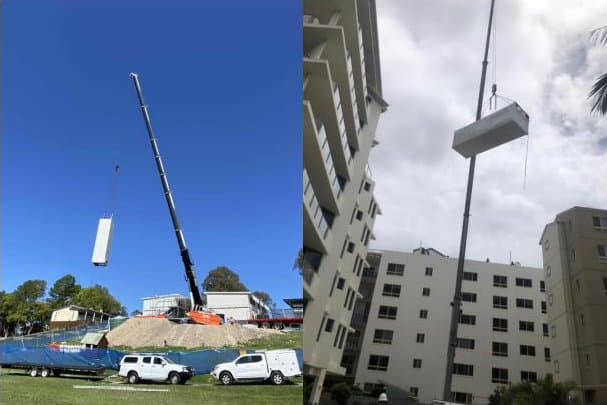 A crane lifting a complete lift shaft over a building site
