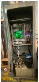 Inside an open machine cabinet: the controller, power supplies, hydraulic tank and pump