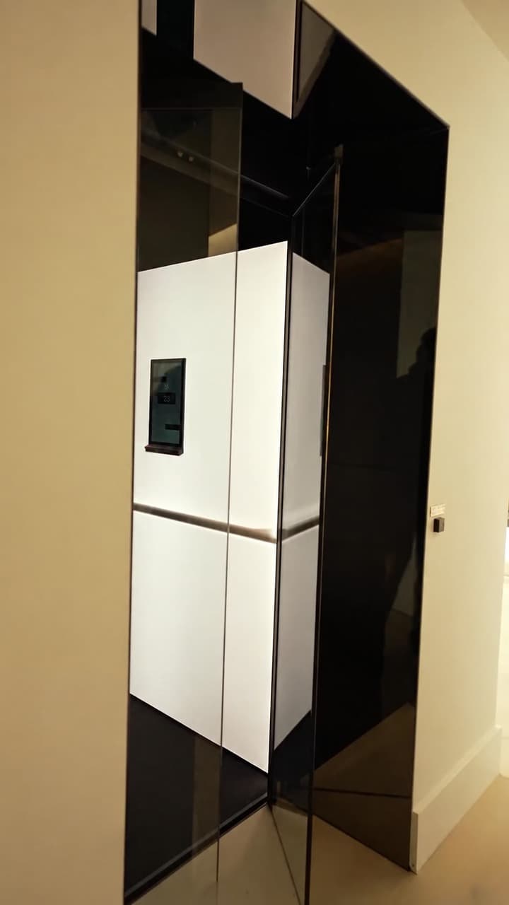 Open glass door into a Jet Black Swift Pro XL cabin with Electric Opal white panels and touchscreen, set in a cream wall in a Broadbeach penthouse on the Gold Coast