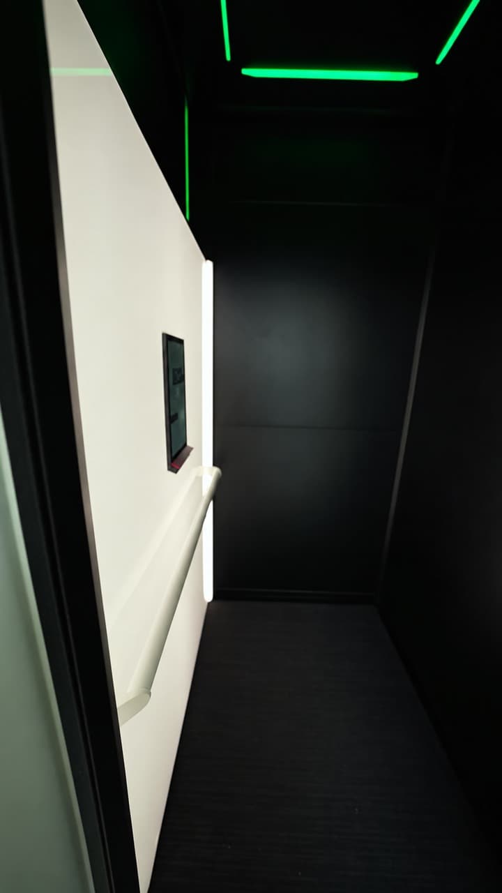 Looking into a Swift Pro XL cabin with Electric Opal white wall, white handrail, Stitch Black floor and green RGB ceiling lighting in a Broadbeach penthouse