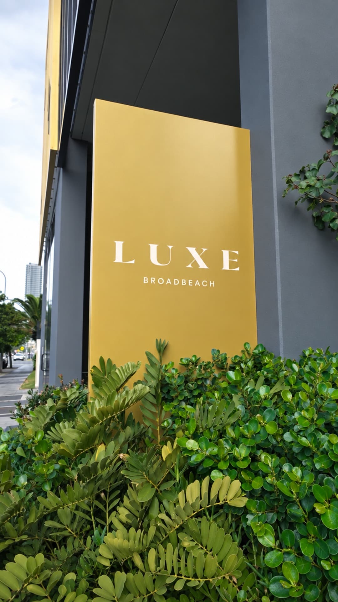 Physical LUXE BROADBEACH building sign at the Gold Coast entry, beside glass doors