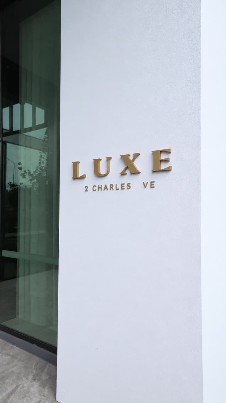 LUXE building sign at 2 Charles Avenue, Broadbeach, Gold Coast, beside glass entry doors