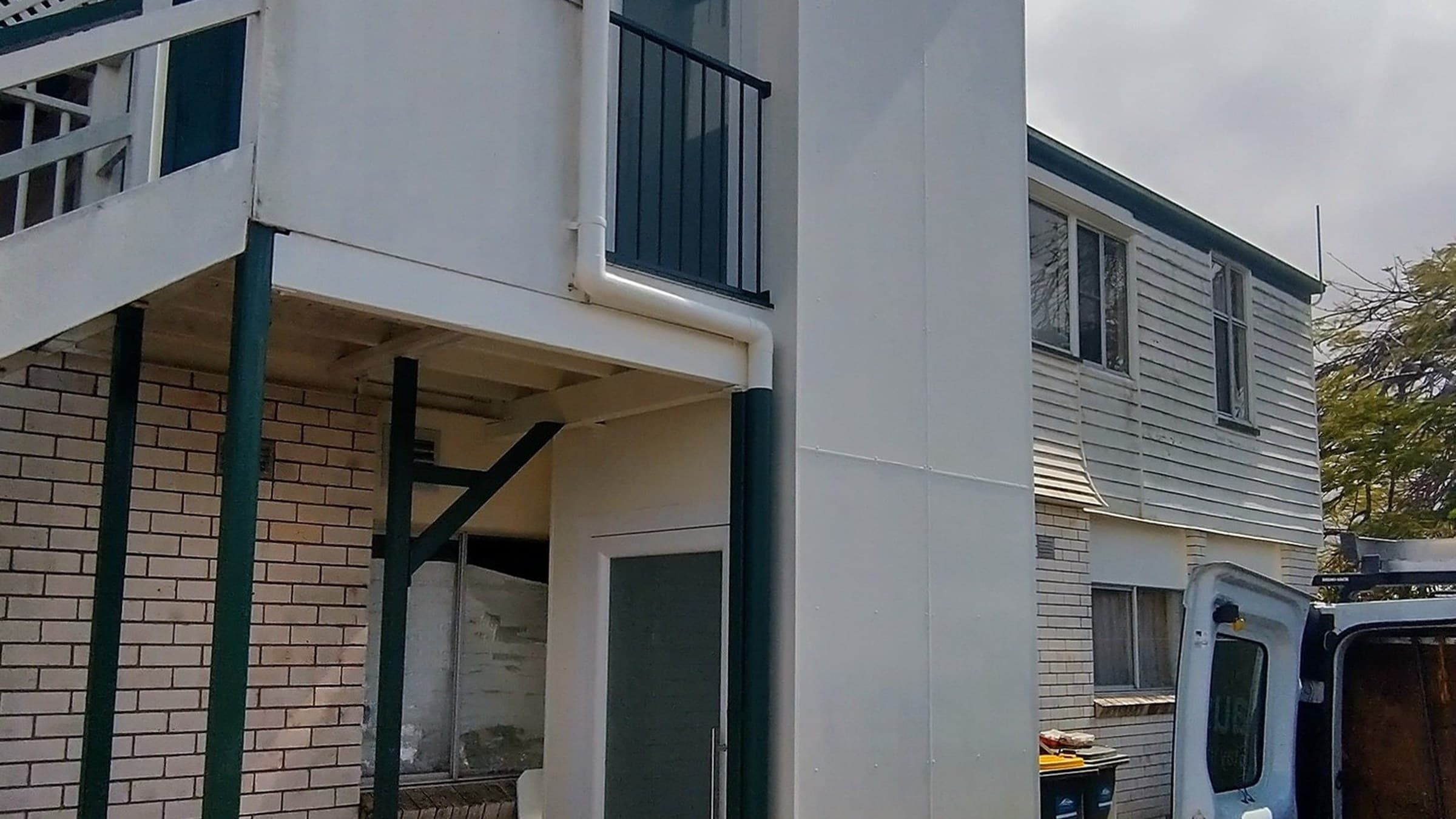 A Phoenix home lift in a Bundaberg, Queensland home, finished white external shaft beside a two-storey house with stairs and an Aussie Lifts van