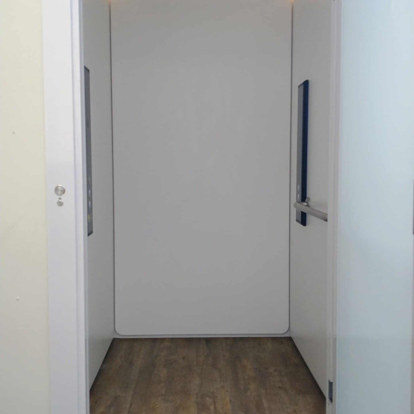 A Phoenix home lift cabin in a Bundaberg, Queensland home, looking in through the open door to white panels, wood floor and control panels