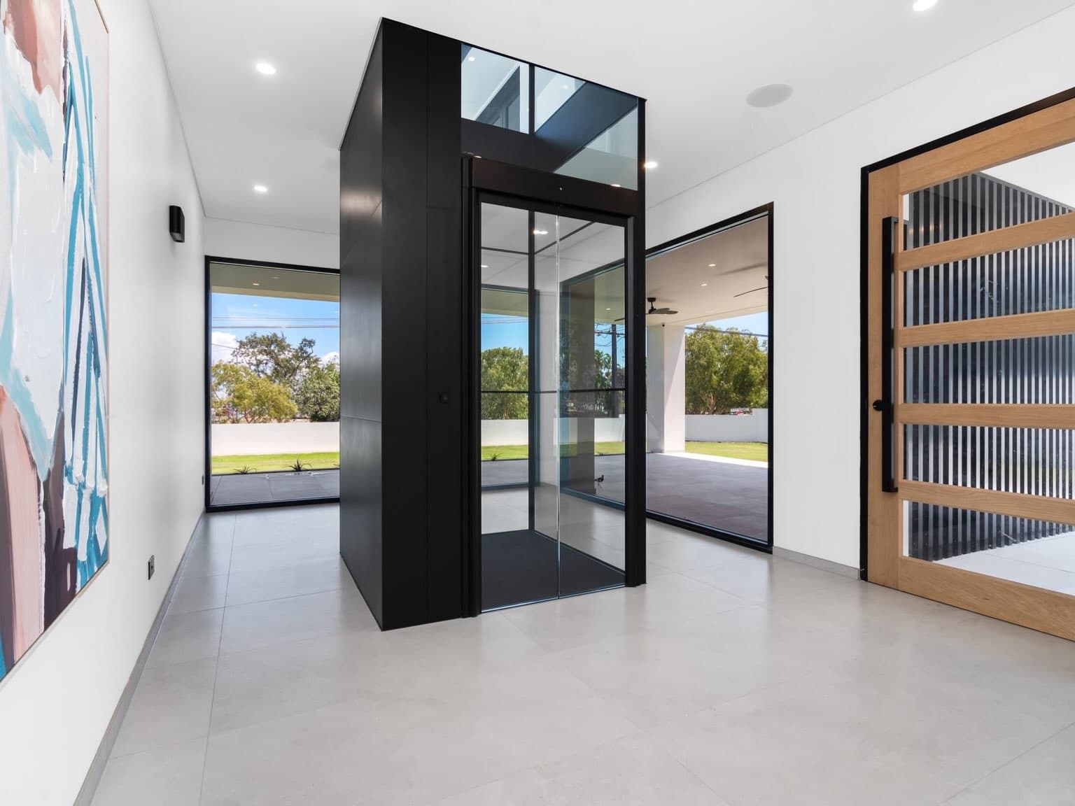 Freestanding Jet Black Swift Pro home lift in a Fannie Bay entry with light tiled floors and a timber and glass front door