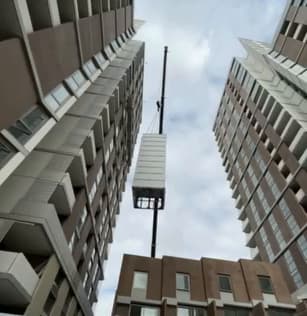 A Phoenix lift being craned into a Macquarie Park, Sydney development by ANC Cranes, the modular shaft rising on the crane line between two residential towers