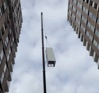 A Phoenix lift being craned into a Macquarie Park, Sydney development by ANC Cranes, looking up at the modular shaft high on the crane against an overcast sky