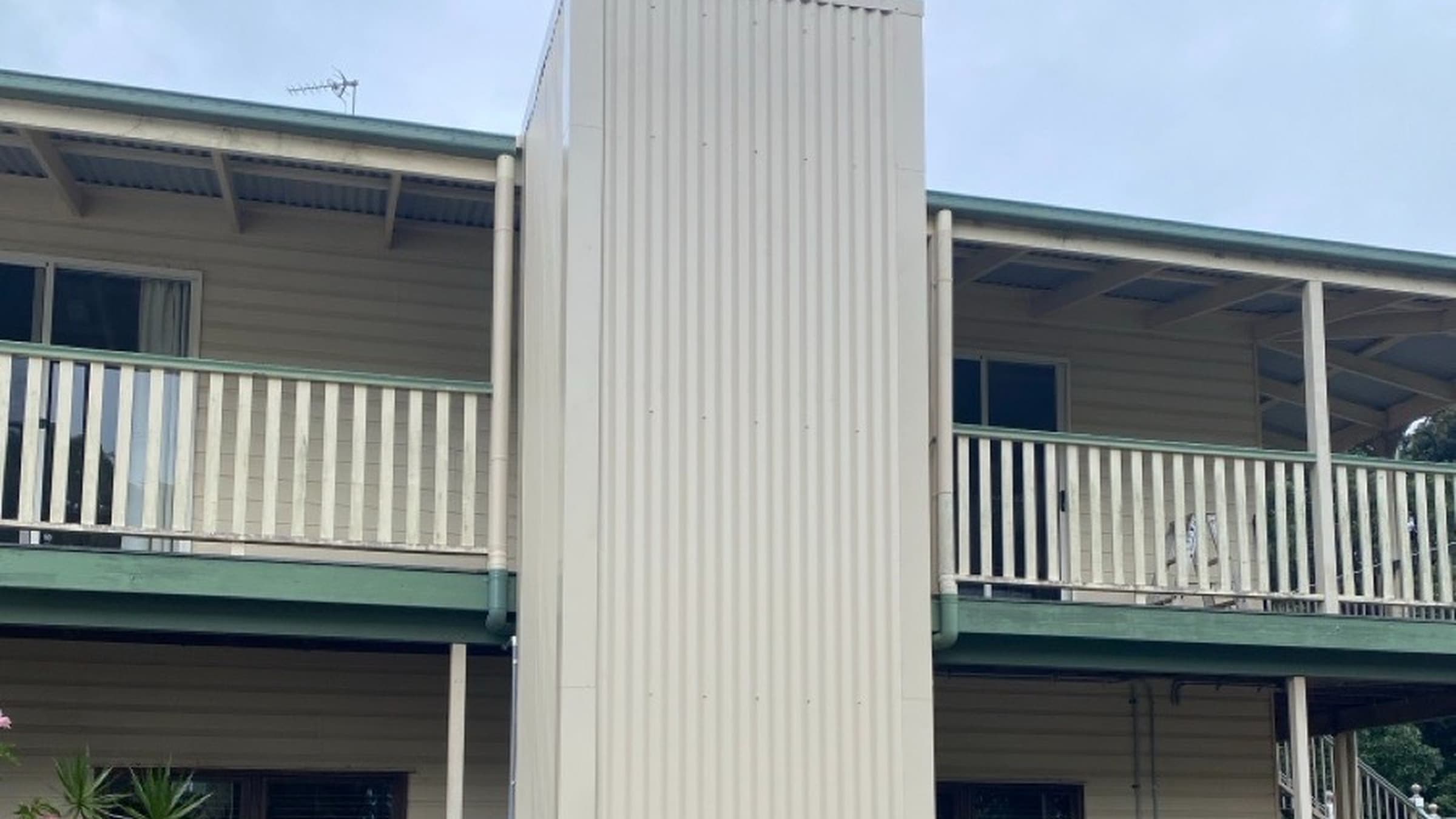 A Phoenix home lift in a Mt Tamborine, Queensland home, after install, with a cream corrugated external shaft on a two-storey Queenslander