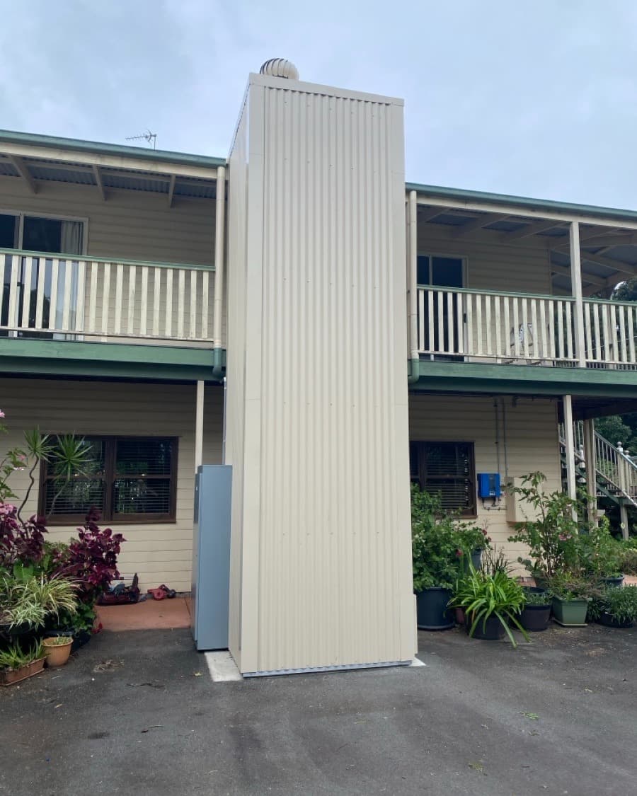 A Phoenix home lift in a Mt Tamborine, Queensland home, after install, cream corrugated external shaft on the house