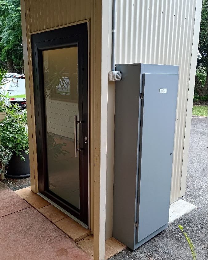 A Phoenix home lift in a Mt Tamborine, Queensland home, ground landing door, grey cabinet and Aussie Lifts van