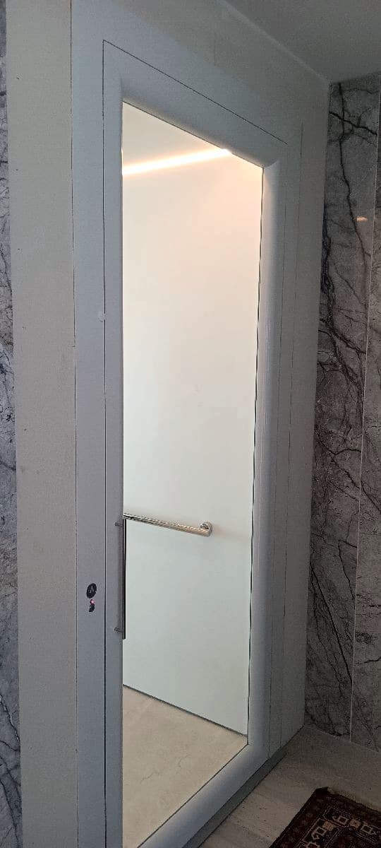 White Phoenix home lift landing door beside a marble feature wall in a Sunrise Beach home, Sunshine Coast